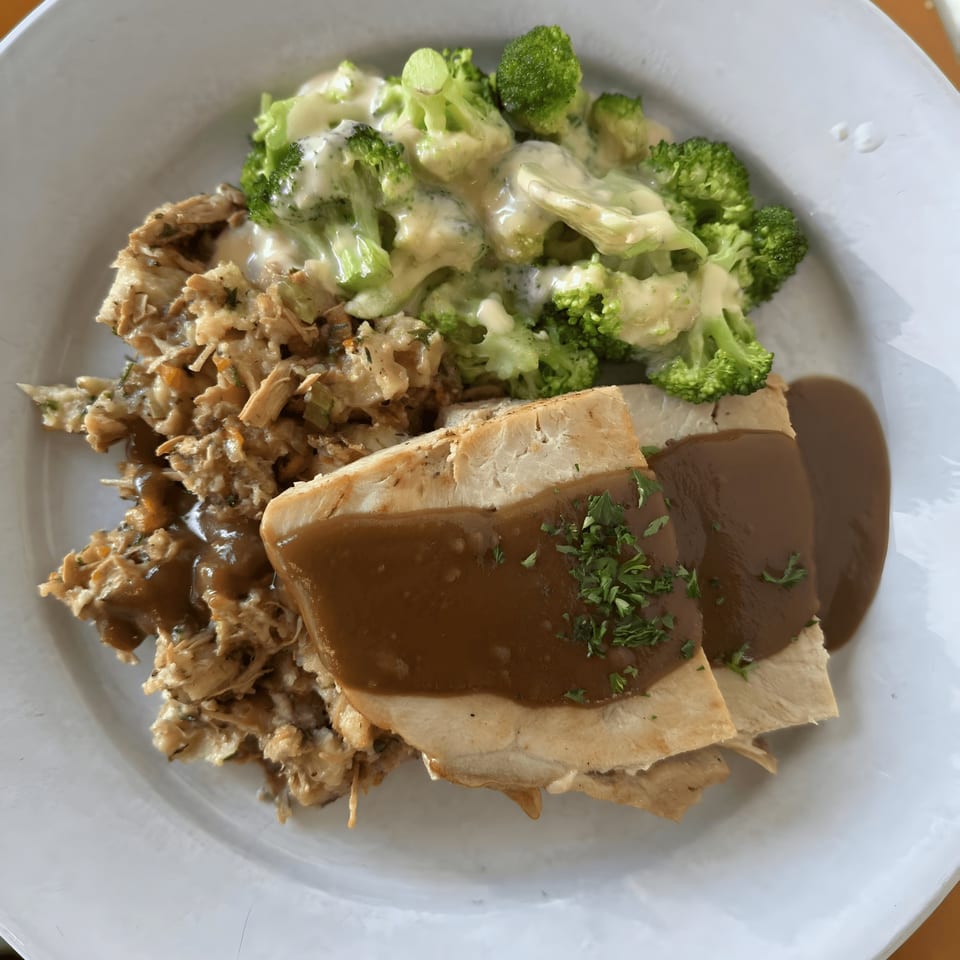 Acme Cafe's American dish with sliced turkey, gravy, stuffing, and broccoli with cheese sauce.